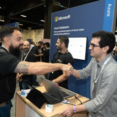 Two men shaking hands in front of an Azure Databases booth 